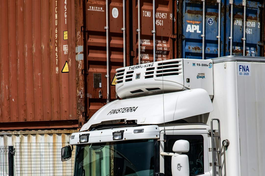 A white truck with shipping containers and stacked wood